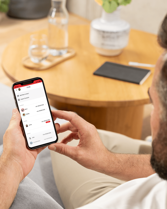 Förälder använder Xplora-appen på mobilen för att hantera kontakter och inställningar för sitt barns smartklocka.