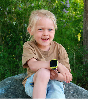 Flicka sitter på sten i skogen med Xplora-klocka – trygg teknik för barn som utforskar naturen.