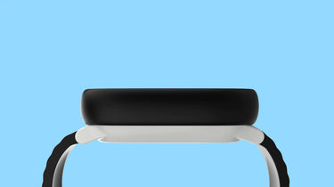 Sidovy av en Xplora smartklocka med svart klockfodral och vit ram, mot en ljusblå bakgrund. Klockan har en rundad design med bekväm passform, och remmen har en strukturerad yta för bättre grepp och komfort.